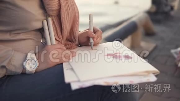 一个女人的手紧紧，靠近大海，一个女人拿着一支笔