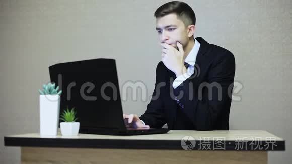 英俊的商人在办公室工作，在笔记本电脑上打字。