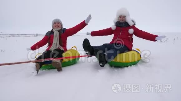 快乐的孩子们玩着雪碟，在冬天霜冻的日子在下雪的冬天的路上笑。 年轻人玩雪橇