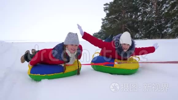 快乐的孩子们玩着雪碟，在冬天霜冻的日子在下雪的冬天的路上笑。 年轻人玩雪橇