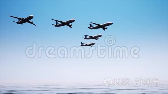 五架飞机在平静的海洋表面与无云的天空之间严格按照特定的顺序飞行。 一大堆飞机。