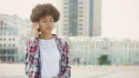 戴着耳机听着最喜欢的歌在户外唱歌的年轻女性