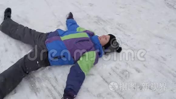 冬天的雪乐趣。 少年躺在雪地里。