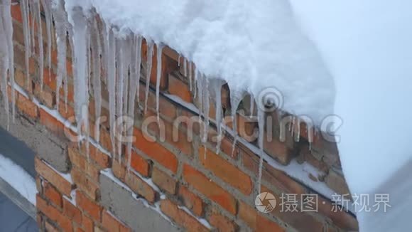 很多冰柱挂在砖墙背景的屋顶上视频