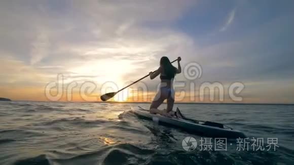 晚上，女性冲浪者在开阔的海洋里骑桨板。 4K.