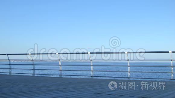 4美丽的女人走在码头上。 蓝色平静的大海在一边