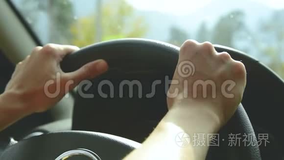 打开光圈的特写。 那个女孩在乡间小路上开车。 女人`把手放在方向盘上