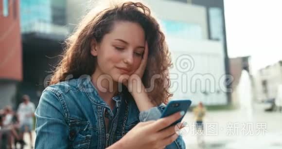 美丽开朗的女孩带着牙套和卷曲的黑发在手机上聊天、发短信和浏览的肖像。