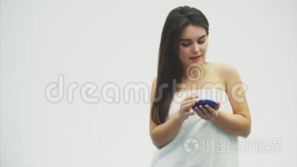 特写快乐的年轻女人在她的脸上涂奶油，护肤和化妆品的概念。 化妆品。 女性面部皮肤护理