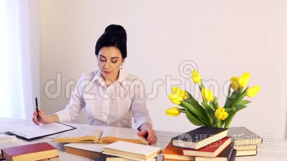 工作太累了，困倦的年轻女人坐在书桌前拿书
