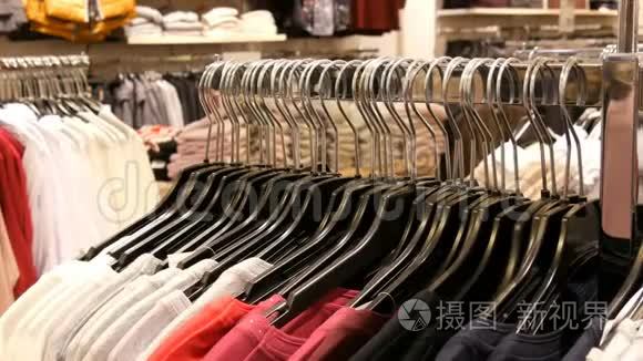 许多不同颜色妇女的衣服挂在衣架上，躺在一家服装店的货架上。