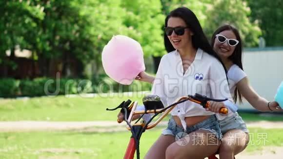 两个穿着短牛仔短裤和白色t恤的黑发小女孩骑着电动摩托车