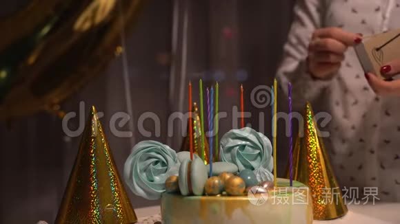 在美味的生日蛋糕上点燃蜡烛的女性手。 准备参加派对。
