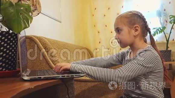 一个小女孩用笔记本电脑工作或玩它。