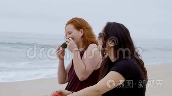 两个女孩在海滩上吃西瓜