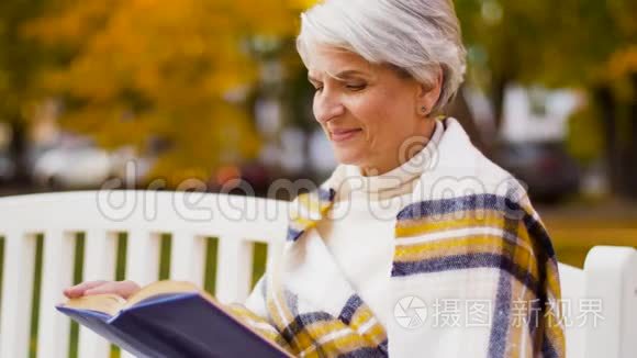 快乐的老年女性在秋公园读书