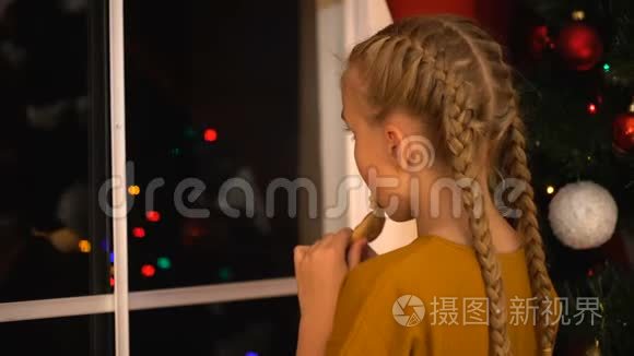 小女孩透过窗户看着吃饼干，等待着父母的圣诞前夜