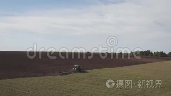 现代拖拉机的鸟瞰大棕色田野。 拖拉机对收获场的空中观察