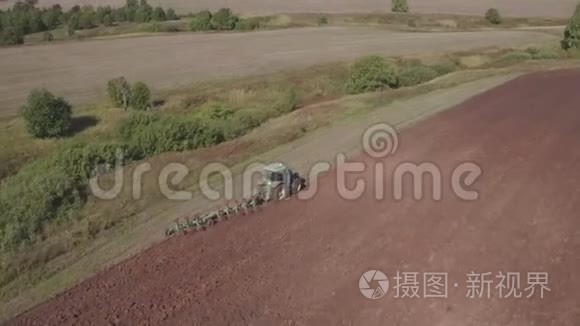 现代拖拉机的鸟瞰大棕色田野。 拖拉机对收获场的空中观察