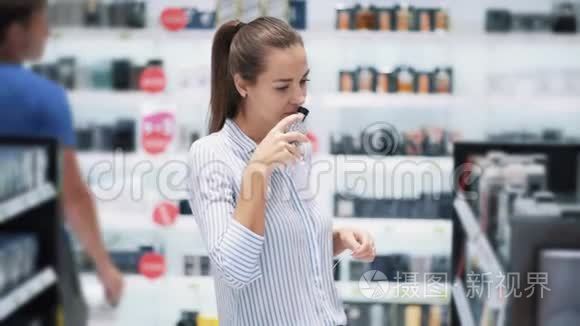 美丽的女孩在化妆品店里选择香水，闻它，慢动作