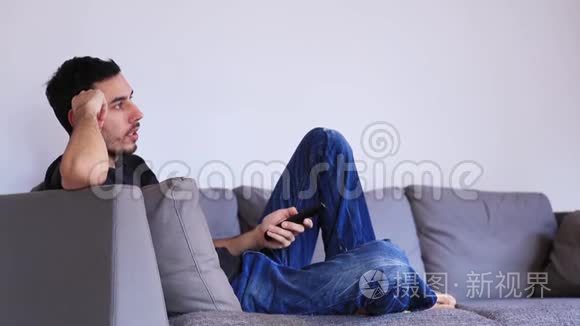 男人坐在沙发上用遥控器看电视视频