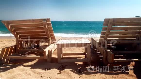 在废弃的海滩上拍摄两张木制日光浴床和一张小桌子的4
