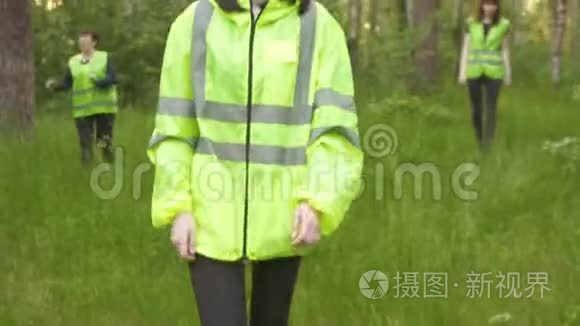 身穿绿色背心的志愿者正在日落时分在树林中寻找失踪人员