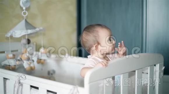 一个小女孩站在婴儿床上仔细地看着一个人