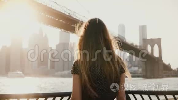 后景的快乐旅游女孩与飞毛欣赏布鲁克林大桥在纽约从路堤，手臂开放。