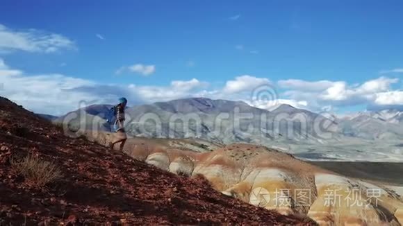 年轻的旅游妇女带着背包和帽子从红石山下来。 不真实的风景和