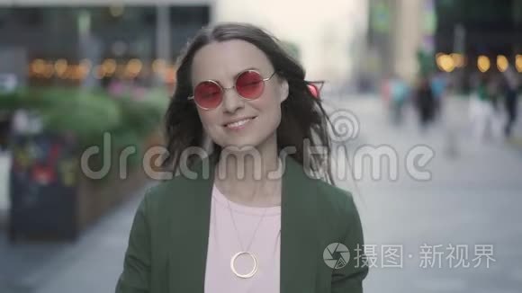 年轻漂亮的女人在秋天的街道上展示胜利标志