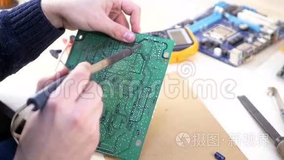 年轻电脑技师焊接绿色主板.
