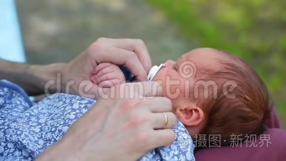 白人父亲和一个新生婴儿坐在公园里。 父母把一个摇摆不定的孩子女儿儿子抱在怀里。 真正的