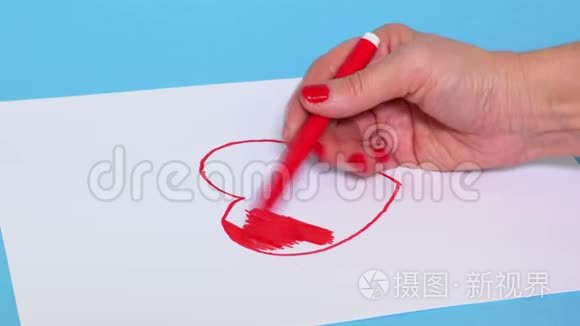 女人在白纸上涂上红色心形图案视频
