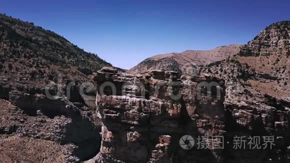 在晴朗的日子里，无人机在巨大的岩石上飞行，以揭示出在高山峡谷山脊之间的美丽的公路道路。