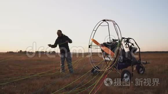 一辆汽车滑翔机的男性驾驶员将降落伞固定在滑翔机的身体上，为飞行做好准备并进行检查