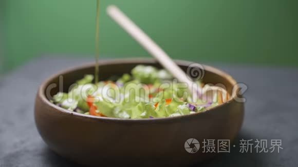 一位女士用橄榄油从各种蔬菜和蔬菜中倒入新鲜沙拉。 健康饮食观念，素食