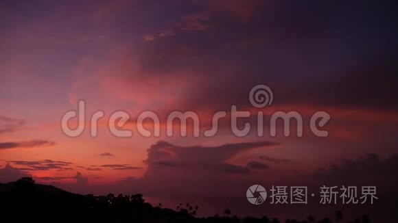 雄伟的热带紫色夏季，夕阳在海面上，群山的轮廓。 戏剧性黄昏的空中景色