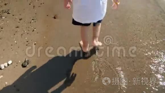 特写4k小男孩在海边沙滩上散步的视频