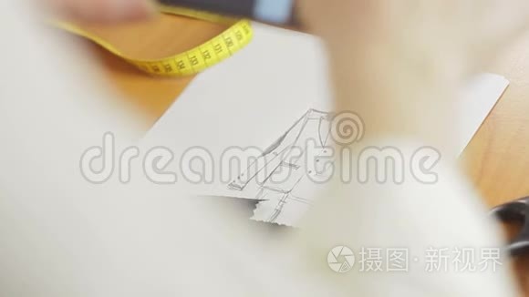 一个女人的手`特写，一个时装设计师在阁楼上画衣服的草图