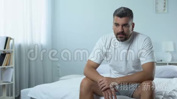 悲伤的失业男人坐在卧室里，想着未来抑郁的计划