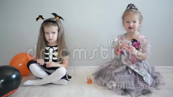 笑滑稽的儿童姐妹女孩在女巫服装庆祝万圣节。 他们有很多乐趣。