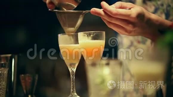 酒保在工作。 在杯子里混合一杯含酒精的鸡尾酒。 从筛子中筛出一种成分