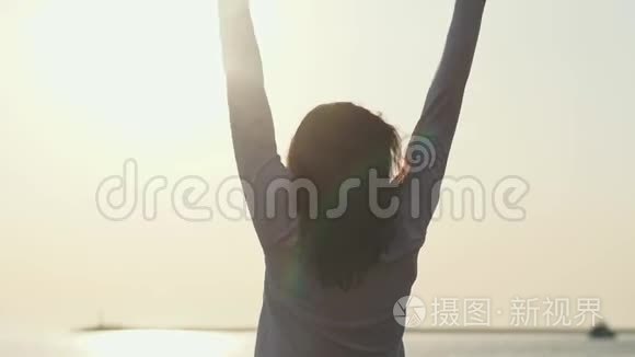 年轻苗条的女人伸出双手站在海上日出前