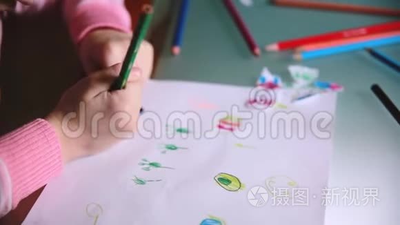 镜头从小白种人的学龄前女孩手中滑落，用彩色铅笔在一张桌子上画动物
