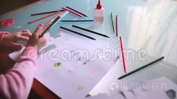 俯视镜头左滑动的小白种人女孩在纸上用各种颜色的铅笔在一张桌子上。