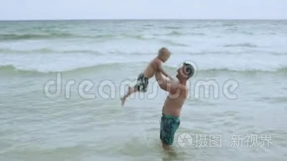 年轻迷人的父亲和他快乐的儿子在美丽的海滩上玩得很开心