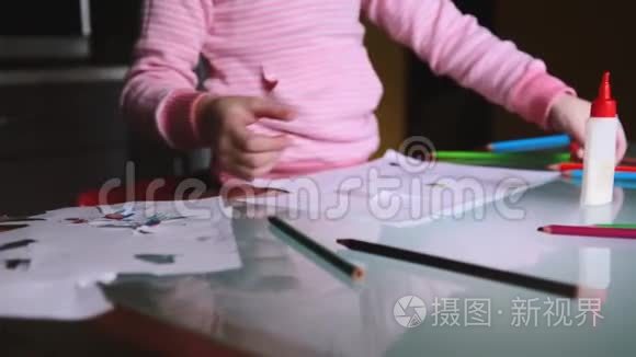 镜头向右滑动，显示穿着粉红色毛衣的欧洲小女孩拿着铅笔在桌子上用文具画画