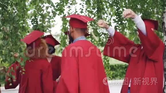 喜气洋洋的男女毕业生穿着长袍戴着帽子，在毕业典礼上互相拥抱祝贺，欢笑和欢笑