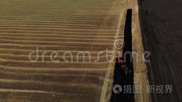 拖拉机耕田，备地播种.. 红色拖拉机。 空中观景。 农民在拖拉机上准备土地